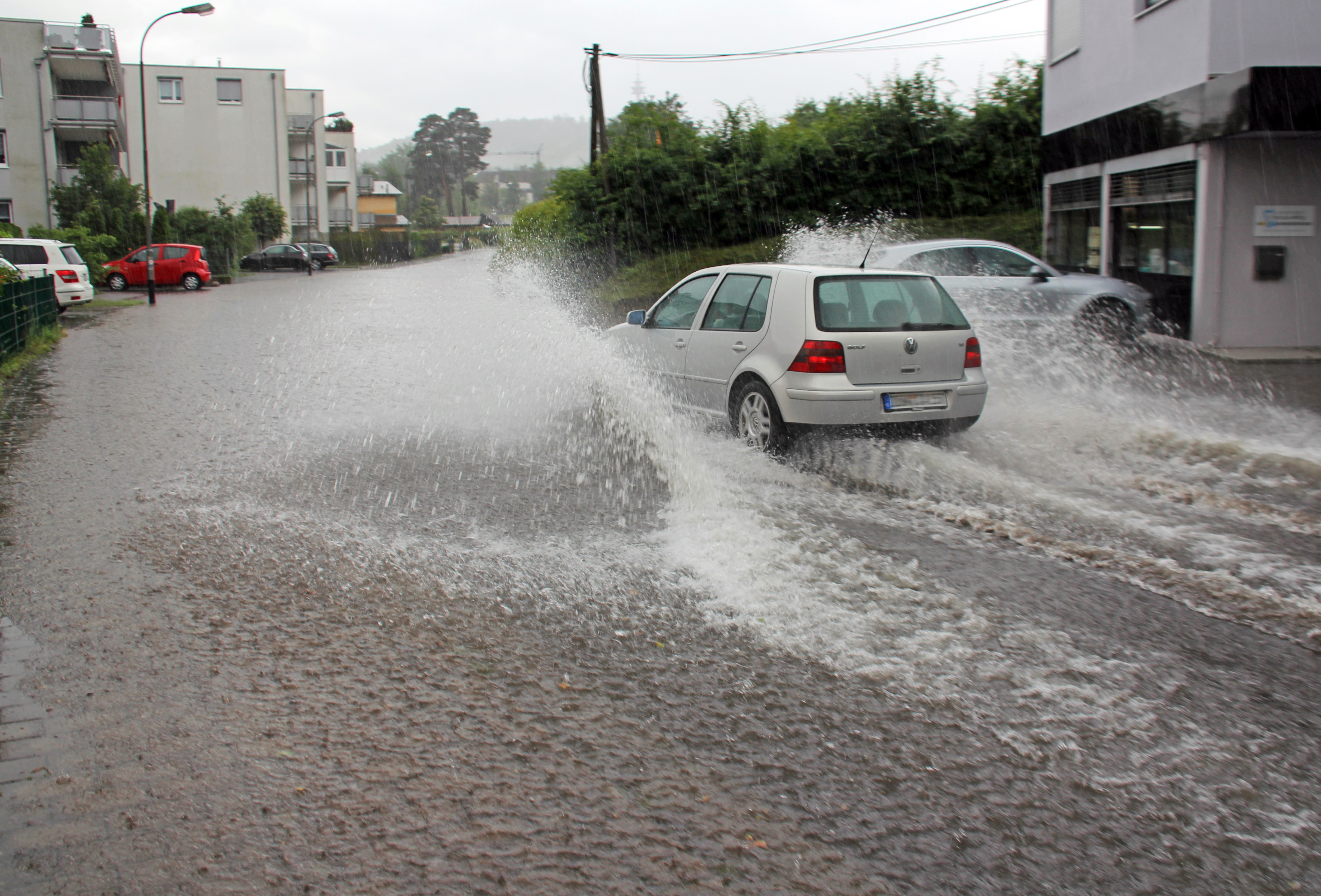 Starkregen in Kaiserslautern Ein Auto fährt im Starkregen durch eine überflutete Straße eines Wohngebietes