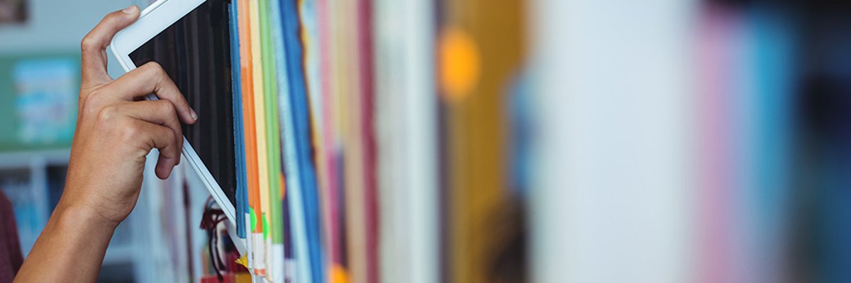 Hand of student keeping digital tablet in bookshelf in library Hand of student keeping digital tablet in bookshelf in library
