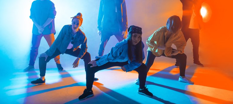 Group of male and female dancers in colorful neon light having fun dancing.