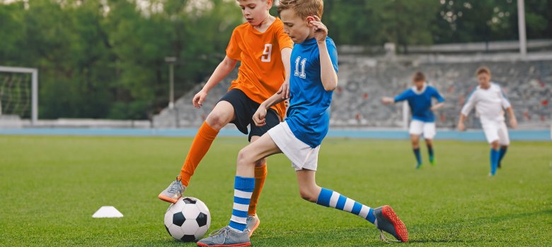 Boys playing football game on a school tournament. Football soccer match for children. Dynamic, action picture of kids competition during playing football