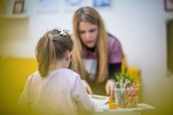 The educator works with a small child in a children's workshop The educator works with a small child in a children's workshop